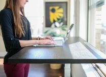 woman in black shirt sitting at the table using macbook