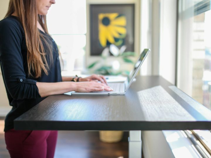 woman in black shirt sitting at the table using macbook